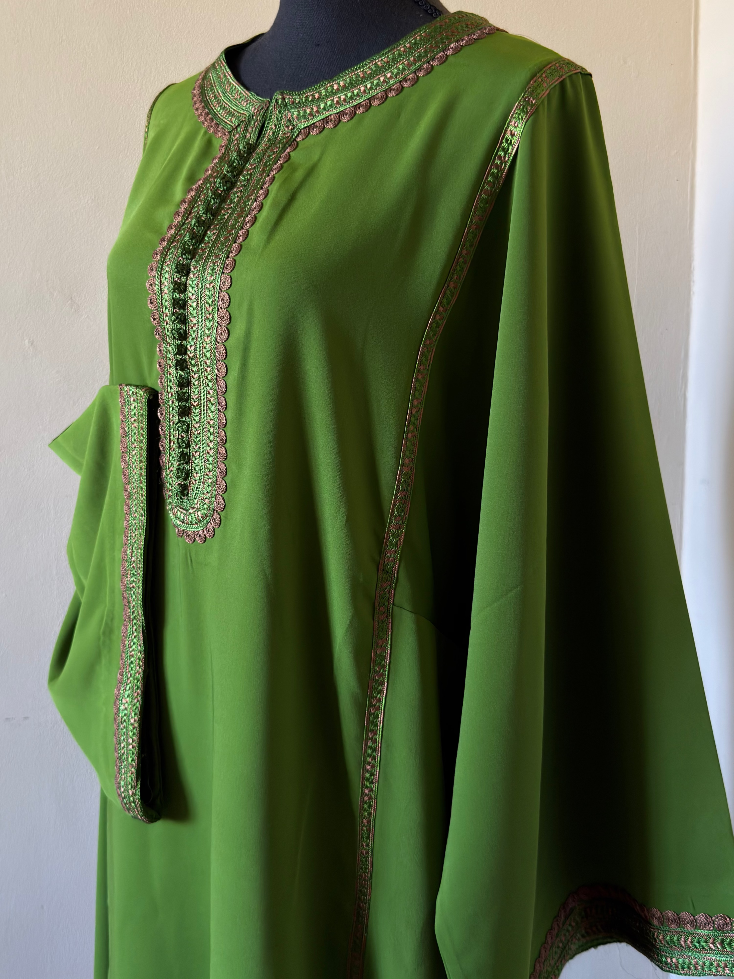 Green dress with intricate embroidery on a mannequin against a neutral background