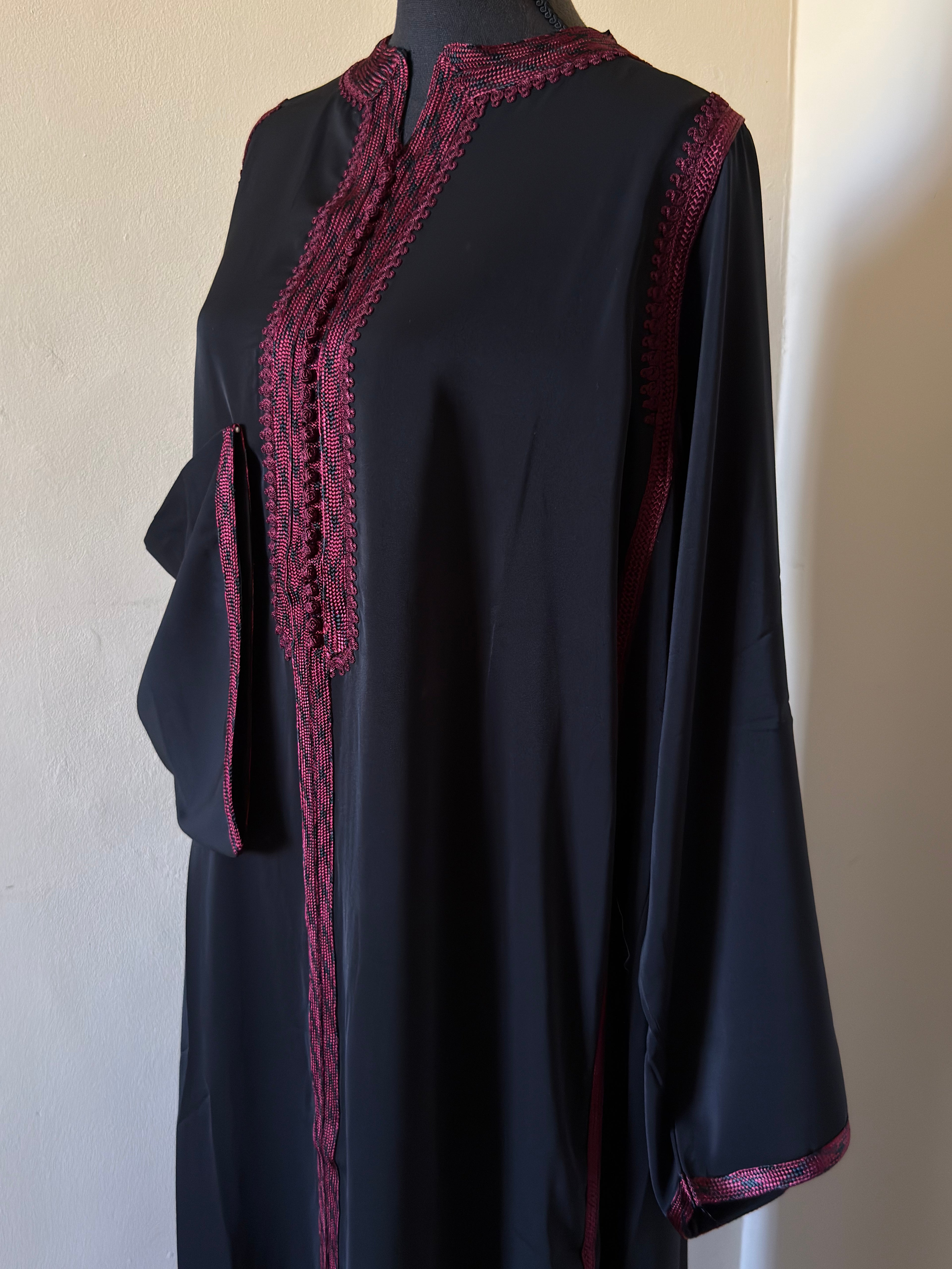 Black dress with red lace details on a mannequin against a plain background
