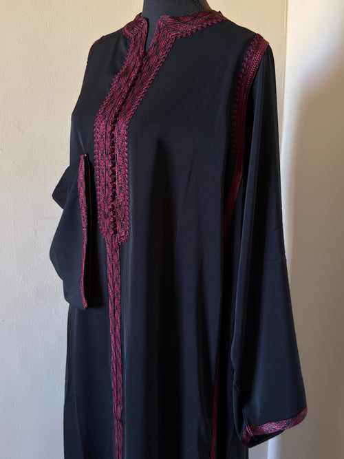 Black dress with red lace details on a mannequin against a plain background