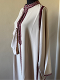 White dress with red lace details on a mannequin against a plain background