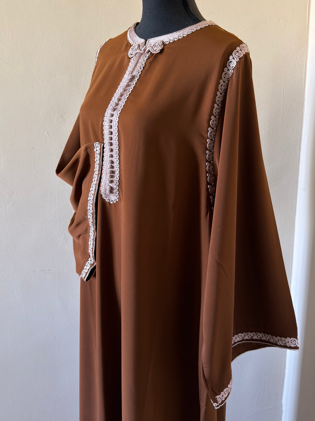 Brown dress with white lace trim on a mannequin against a plain background
